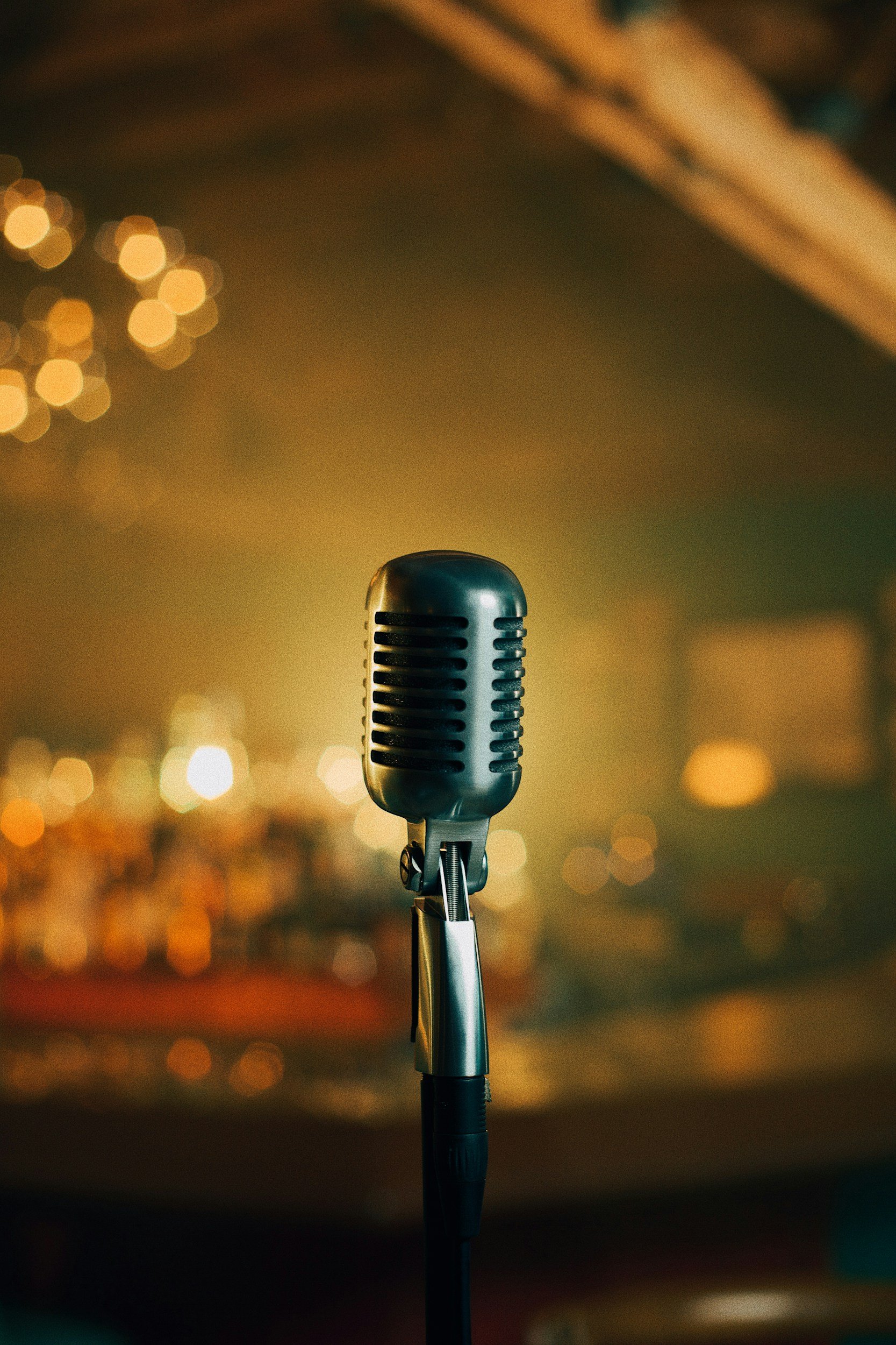 An old fashioned standing mic, in front of an ambient, warmly lit room.